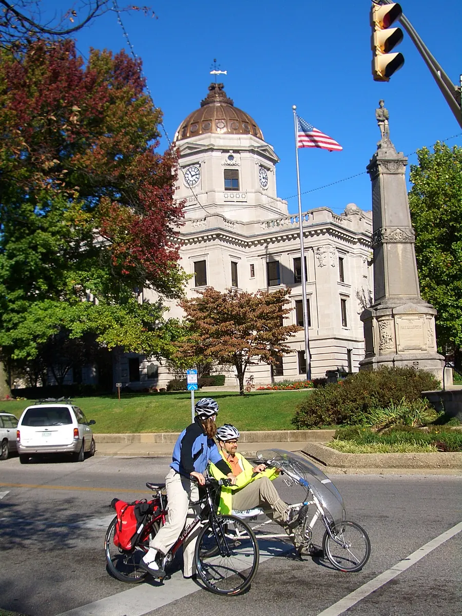 The Monroe County Courthouse on a clear autumn day, two cyclists crossing in front of it